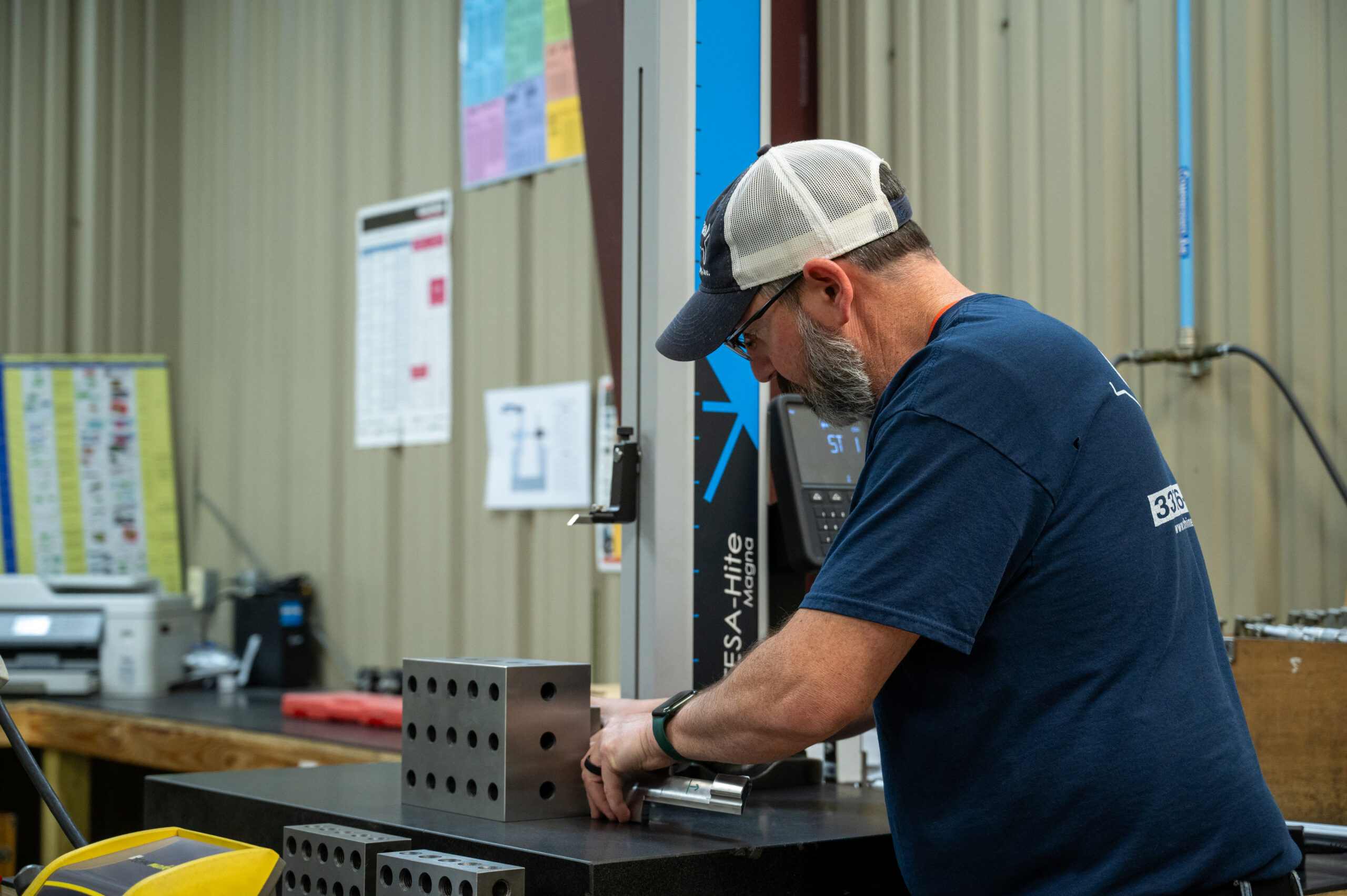 Coastal Machine Manufacturing worker examining metal part for defense customer