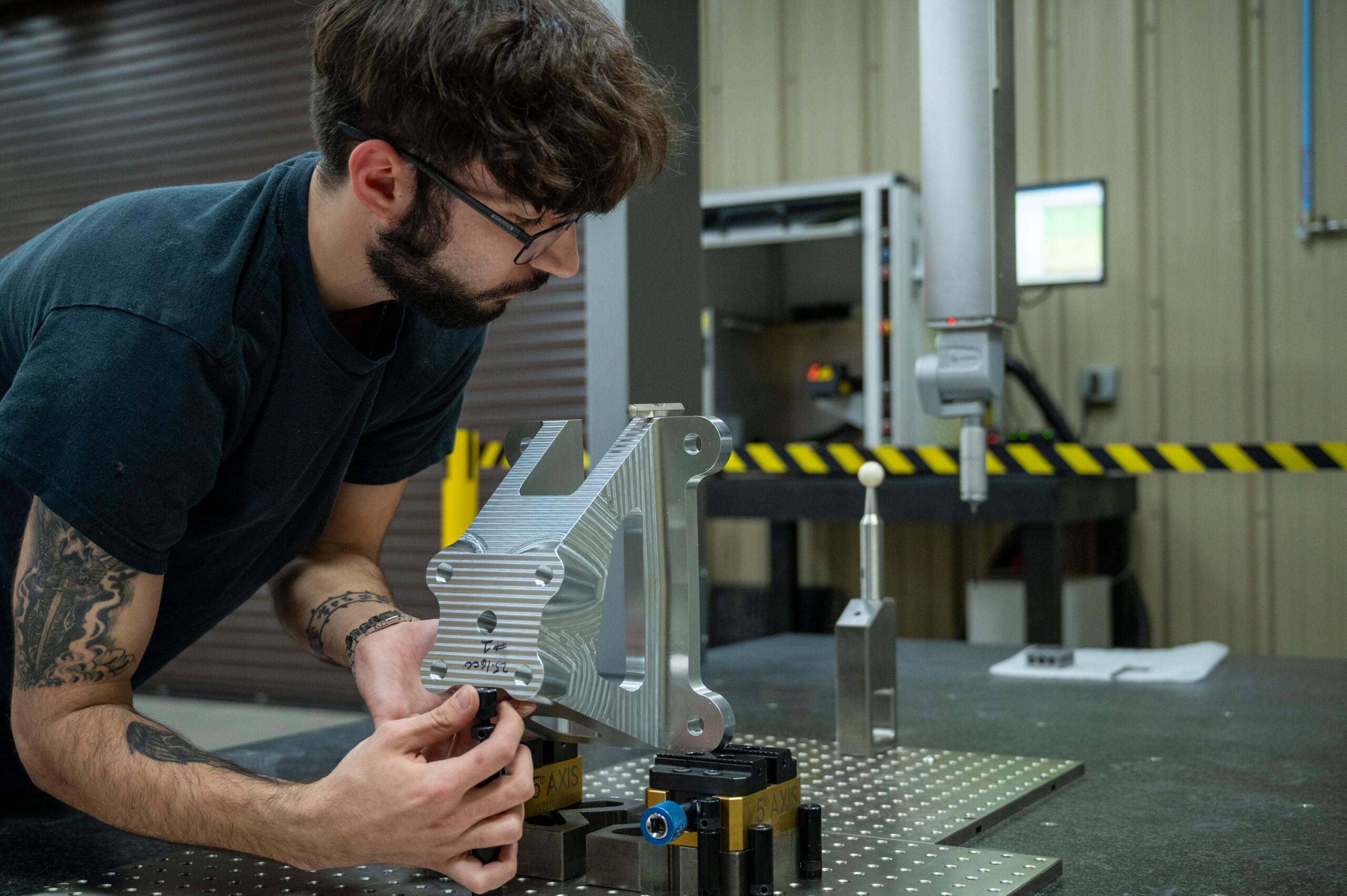 Machinist using a CMM (coordinate measurement machine) to examine quality metal parts