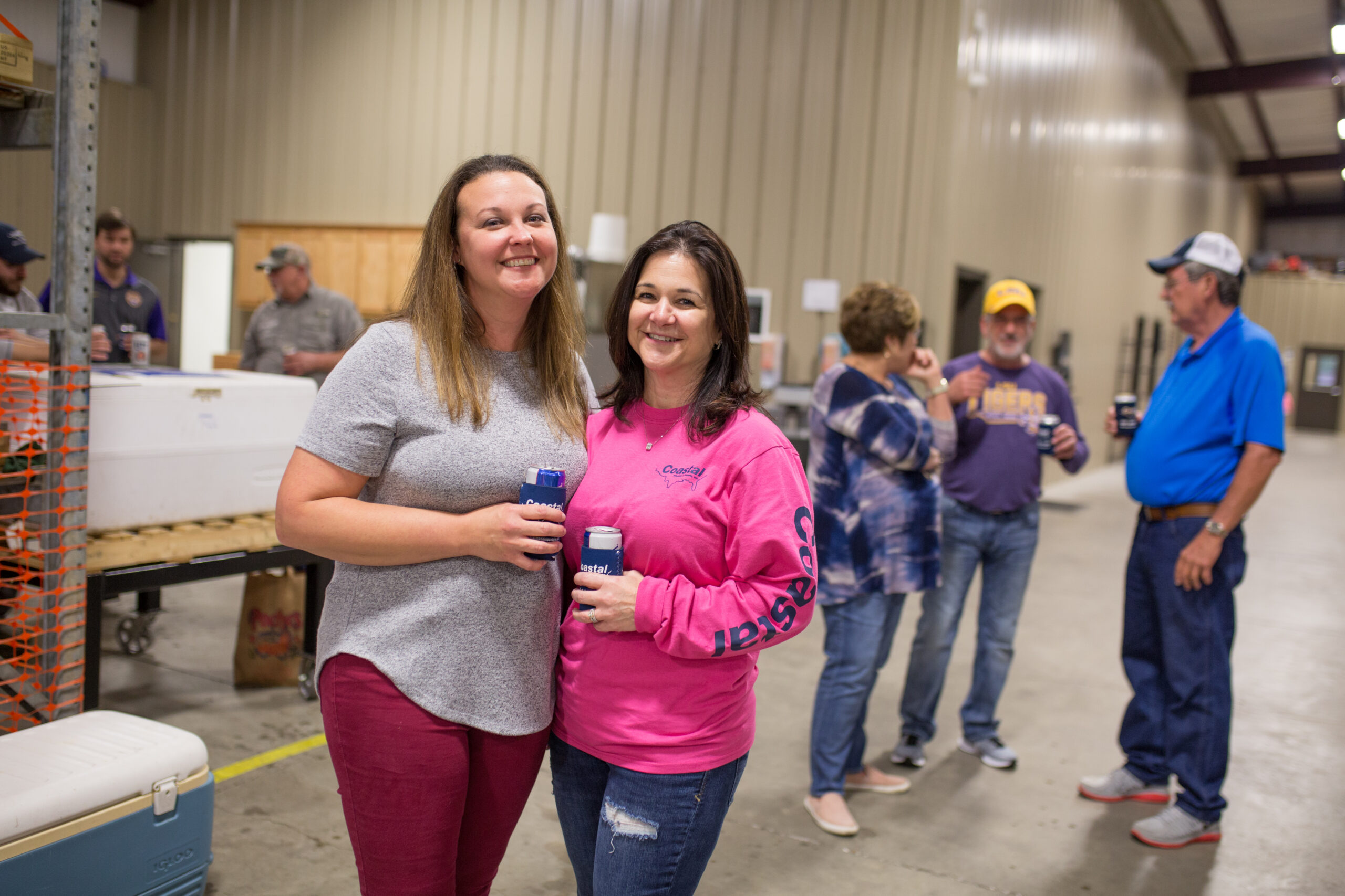 Two women holding beers at a Crawfish Boil in Louisiana manufacturing facility