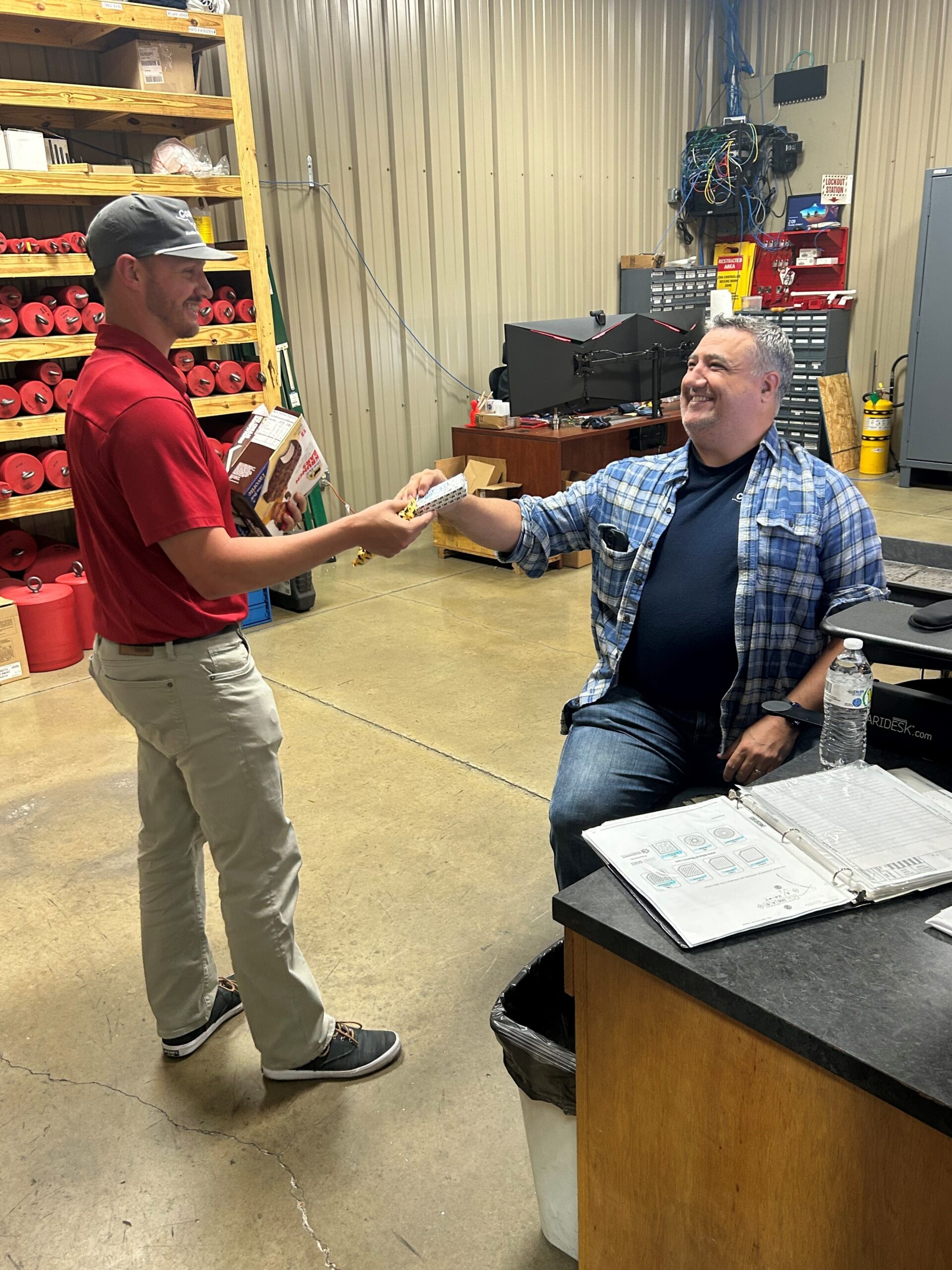 Kody Guidry, Manager of Coastal Machine & Supply, handing an ice cream sandwich to an employee
